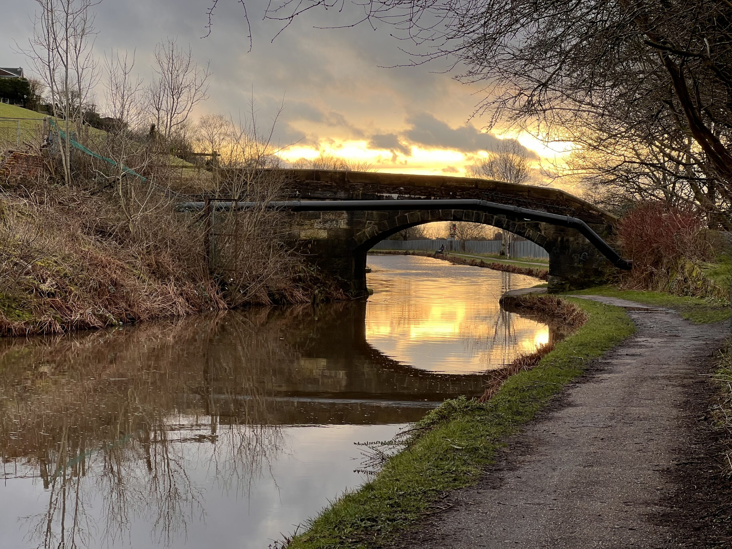 A photograph of the sun setting behind a bridge over the Rochdale Canal